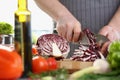 Closeup of a male cook hand using knife slicing fresh red cabbage on cutting board in kitchen at home Royalty Free Stock Photo