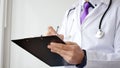 Closeup of male doctor hand writing a medical prescription