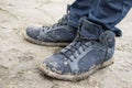 Closeup of male feet wearing jeans and dirty shoes standing on country road. Royalty Free Stock Photo