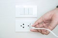 Closeup Male finger unplugging or plugging of electricity device on white wall at home. Energy Saving, power, electrical and