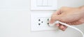 Closeup Male finger unplugging or plugging of electricity device on white wall at home. Energy Saving, power, electrical and