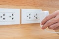 Closeup Male finger unplugging or plugging of electricity device on white wall at home. Energy Saving, power, electrical and