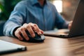 Closeup Male hand clicks wireless digital mouse at office desk Royalty Free Stock Photo