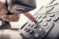 Closeup of male hand holding telephone receiver while dialing a Royalty Free Stock Photo