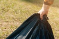 Closeup male hand holds a big black bag with things. concept of garbage collection on the street on summer day