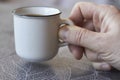 Close-up of male hand holds a small white cup with black coffee on gray background, selective focus Royalty Free Stock Photo