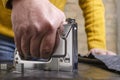 Closeup of male hand and metalic staple gun.Process of fixing of furniture, black leather