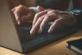 Closeup of male hands typing laptop computer keyboard at office desk, businessman working late at night Royalty Free Stock Photo