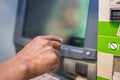 Closeup of male hands using smart phone while typing on ATM, bank machine. Man hand entering on screen at an ATM Royalty Free Stock Photo