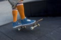 Closeup of male legs with orange socks and blue shoes on a skateboard