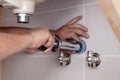 Closeup male plumber's hand fixing sink in bathroom with tile wall. Professional plumbing repair service, installation of water Royalty Free Stock Photo