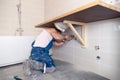 Closeup male plumber worker in blue denim uniform, overalls, fixing sink in bathroom with tile wall. Professional plumbing repair Royalty Free Stock Photo