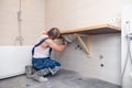 Closeup male plumber worker in blue denim uniform, overalls, fixing sink in bathroom with tile wall. Professional plumbing repair Royalty Free Stock Photo