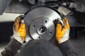 Closeup male tehnician mechanic greasy hands in gloves install new car oem brake steel rotor disk during service at