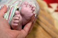 Closeup of a male's hand holding a newborn baby's tiny feet Royalty Free Stock Photo