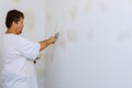 Man aligning a wall with spatula working with putty and spatula wall