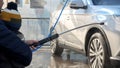 Closeup of man with baby boy washing car at carwash with water jet. Automobile care, transport cleaning, dirty car Royalty Free Stock Photo