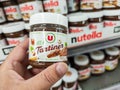 Closeup of Man hand buying dispenser brand of jar of hazelnut cream in french supermaket shelf