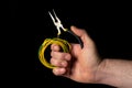 Closeup of a man hand holding diagonal pliers and wire on black background. Commonly used to repair electricity Royalty Free Stock Photo