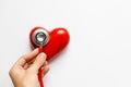 Closeup of man hand holding a red stethoscope on heart - medical diagnostic device for auscultation listening of sounds coming Royalty Free Stock Photo