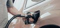 Closeup of man hand holds black gas pump nozzle pouring gasoline into the fuel tank of a vehicle Royalty Free Stock Photo