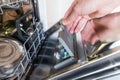 Closeup of man hand putting tablet in dishwasher detergent box, soft focus. Dirty dishes concept