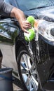 Closeup man hand washing new black car with big soft sponge, soap suds and bucket Royalty Free Stock Photo