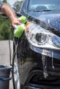 Closeup man hand washing new black car with big soft sponge, soap suds and bucket Royalty Free Stock Photo