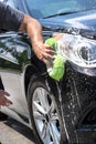 Closeup man hand washing new black car with big soft sponge, soap suds and bucket Royalty Free Stock Photo