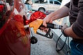 Closeup man hands handle tool refueling gasoline pump into red car