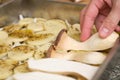 Closeup of man hands placing sliced king trumpet mushrooms pleurotus eryngii over seasoned potatoes and onions Royalty Free Stock Photo