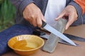 Closeup man hands sharpen knife on whetstone sharpener or grindstone. Royalty Free Stock Photo