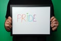 Closeup of a man holding a whiteboard with "pride" written on it in colorful markers - pride concept Royalty Free Stock Photo