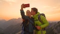 CLOSEUP: Man kisses his smiling girlfriend taking a photo of them in the Alps. Royalty Free Stock Photo