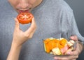 Closeup man mouth, eating a piece of tomato from woman hand while holding fruit salad bowl Royalty Free Stock Photo