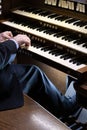 Closeup of a man playing the black and white piano-like keys of a pipe organ in church Royalty Free Stock Photo