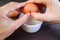 Closeup of man`s hand cracking an egg into a bowl