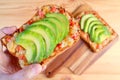 Closeup man`s hand holding a delectable grilled cheese toast with tomato and sliced fresh avocado Royalty Free Stock Photo