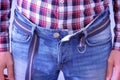 Man hardly buckles the belt of the jeans, pulling the stomach, hands closeup.