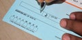 Closeup on manÃ¢â¬â¢s hands writing a cheque. A generic blank cheque being signed