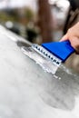 Closeup, man is scratching ice off the car windscreen with a ice scraper Royalty Free Stock Photo