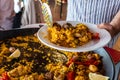 Closeup of a Man serving typical paella from Valencia (Spain) on white plates in a restaurant