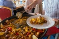 Closeup of a Man serving typical paella from Valencia (Spain) on white plates in a restaurant