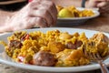 Closeup of a Man serving typical paella from Valencia (Spain) on white plates in a restaurant