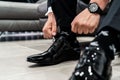 Closeup of a man tying his luxury shiny black leather shoes