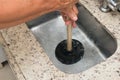 Closeup of the man using a plunger to unstop the kitchen sink. Royalty Free Stock Photo