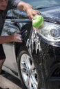 Closeup man washing new black car with big soft sponge, soap suds and bucket Royalty Free Stock Photo