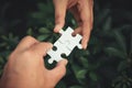 Closeup of man and woman hands connecting jigsaw puzzle together