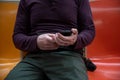 Closeup of man's hands looking at phone on subway seat