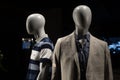 Closeup of mannequins with a suit and a t-shirt on them against a dark bac